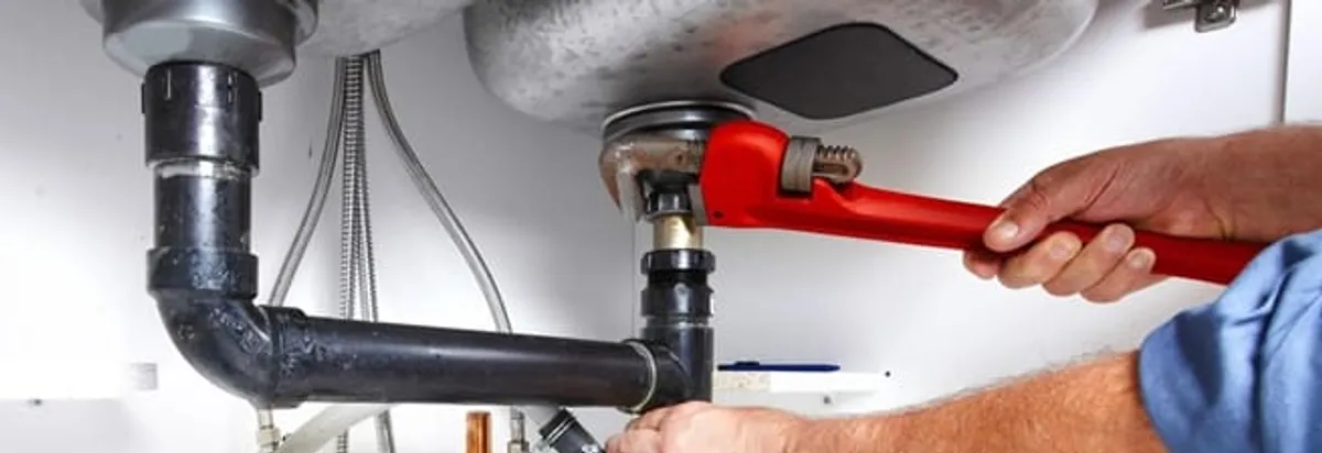 Garbage disposal repair technician tightening the sink drain and disposal connection in San Diego, CA