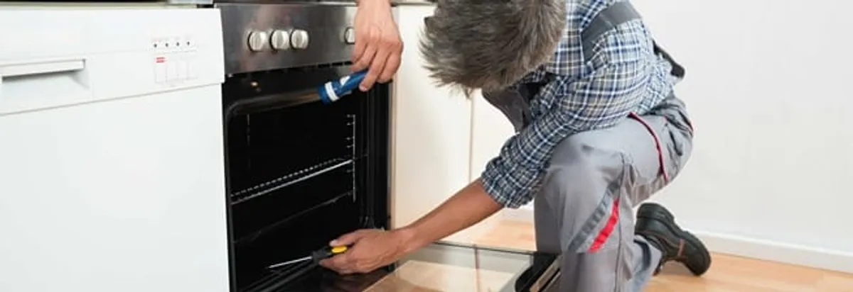 Oven repair technician inspecting and servicing an electric oven in San Diego, CA