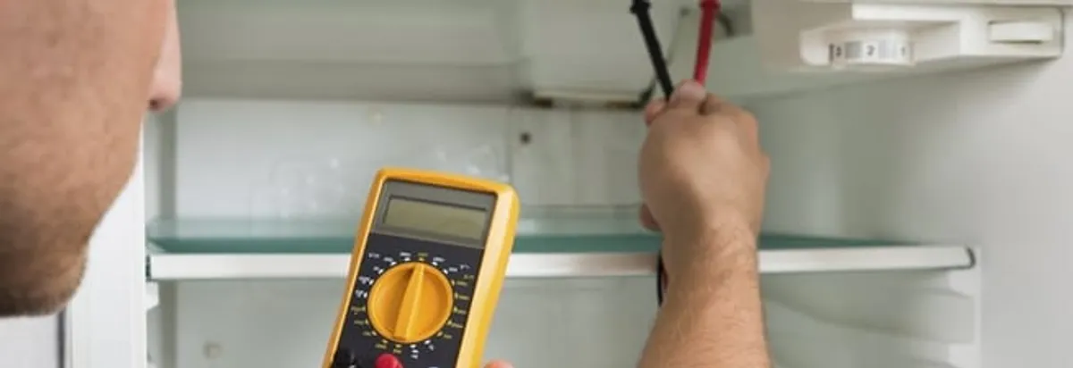 Refrigerator repair technician testing electrical components with a multimeter in San Diego, CA